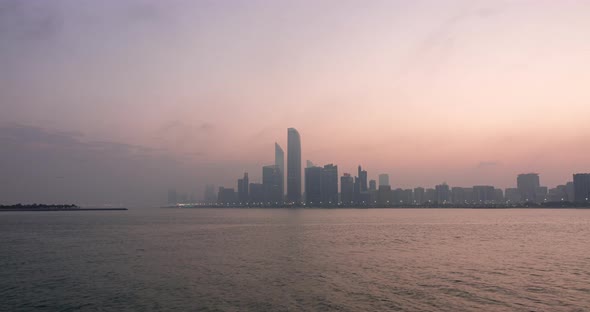 Abu Dhabi City Skyline with Skyscrapers Before Sunrise with Water Reflection Night to Day Transition