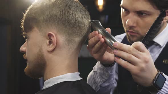 Handsome Professioanl Barber Stylign Hair of a Man