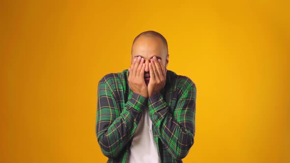 African American Man Closing Eyes with Hands and Smiling Against Yellow Background