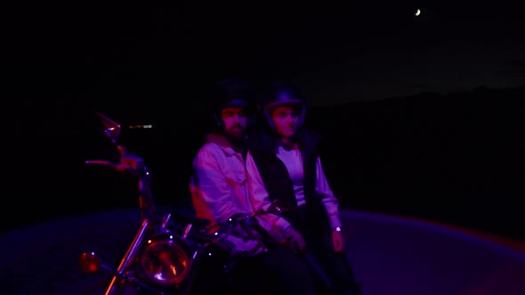 Young Couple Sitting On Motorbike At Night With Red Light Effect. - dolly