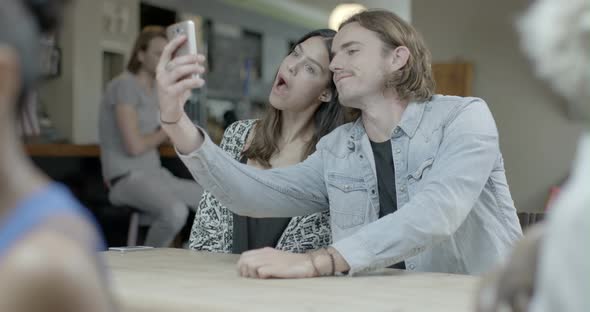 Man and woman taking self photograph with mobile phone in pub