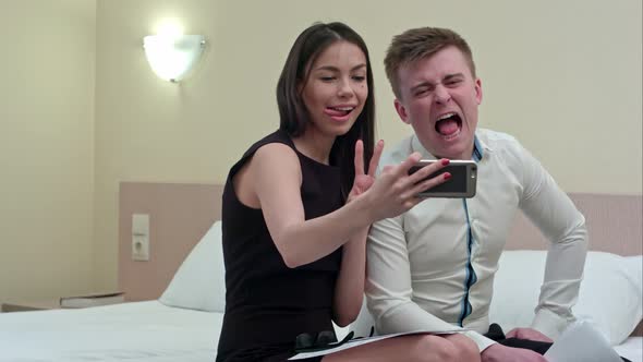 Couple Having Fun Taking Selfie Sitting on Bed in the Hotel Room