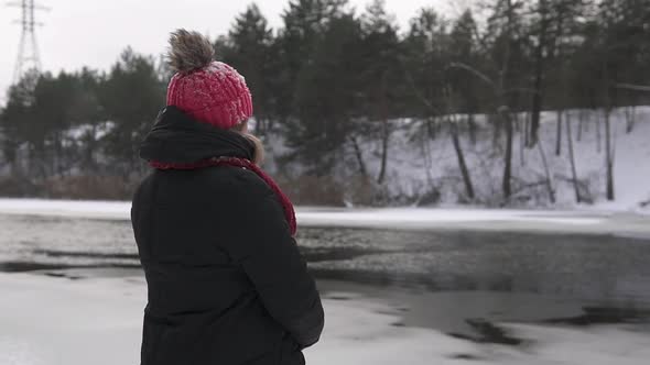 A beautiful girl in the winter forest near the river enjoys nature