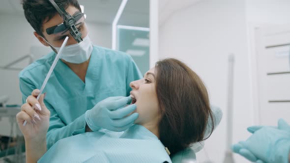 Young Woman Patient and Dentist with Probe Are Checking Teeth at Mirror After Dental Treatment in