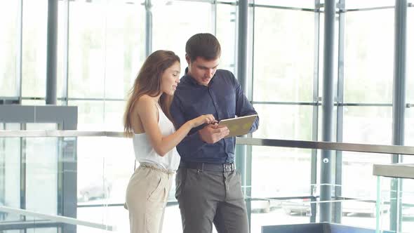 Young Couple of European Appearance Chooses a Car in the Showroom