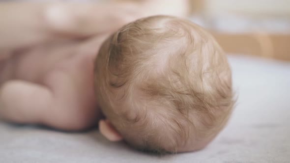 Little Newborn Boy Lies and Pediatrician Practices Massage