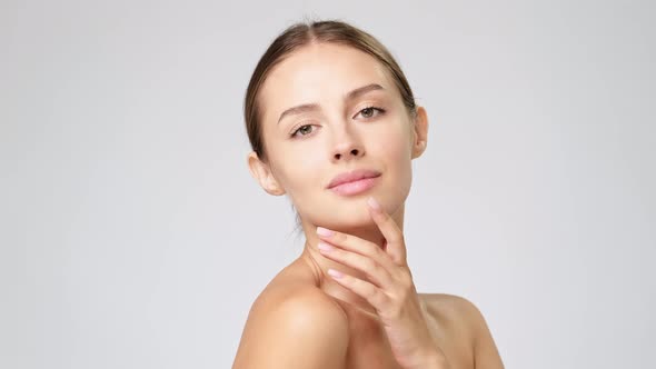 Beautiful Young Woman with Clean Fresh Skin Standing Over Light Grey Background