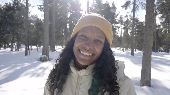 Portrait of Happy African American Woman Looking at the Camera Standing in a Snowy Forest in a