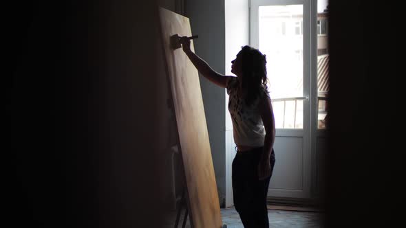 Young Woman Artist Paints New Abstract Painting in Studio Using Wide Brush, Oil Paint. The Girl