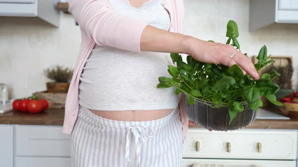 Pregnant Woman Holding Fresh Organic Spinach On Kitchen. Healthy Pregnancy Concept