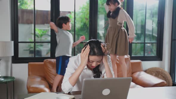 Asian business mother loss her concentration on job in computer because the kids making noise.