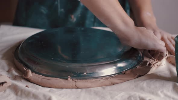 Potter Forming Clay Into a Dish By Using a Form and Tools To Get the Perfect Shape