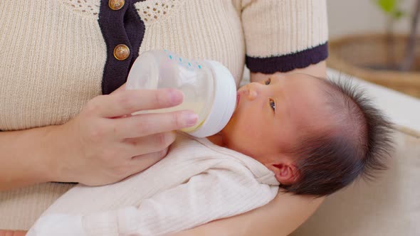 Close up Newborn baby drinking milk from bottle on mom arms