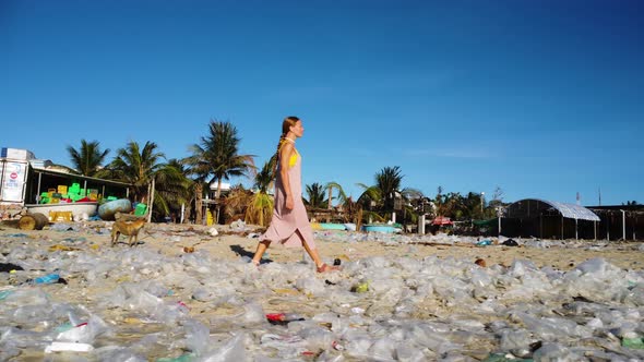 Caucasian woman walking in sandals on polluted beach with plastic bag waste, toxic garbage, ocean po