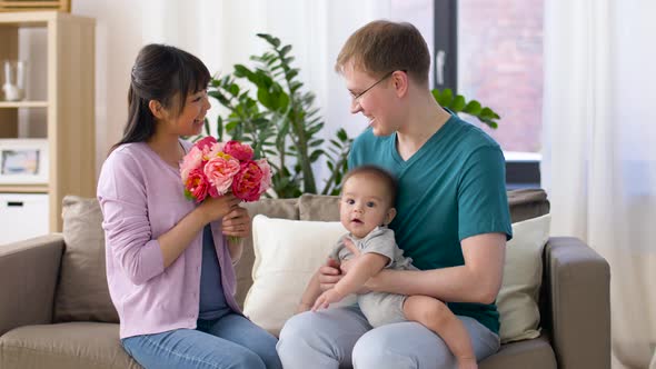 Happy Family with Flowers and Baby Boy at Home 