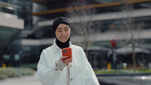 Muslim Woman Surfing Internet on Smartphone at Mall