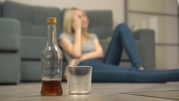 A young woman sleeps after drinking at home on the floor. Female alcoholism