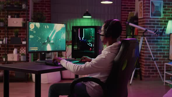 African American Man Playing Fast Paced Multiplayer Space Shooter Using Pc Gaming Setup Having a