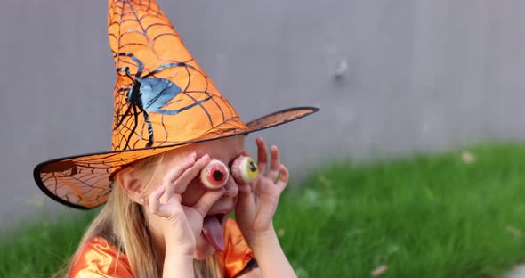 Cute Little Caucasian Girl with Blonde Hair Seven Years Old in Costume of Witch with Hat and Black