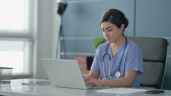 Indian Female Doctor Thinking while Working on Laptop in Office