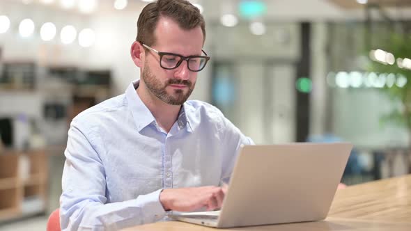 Serious Businessman with Laptop Looking at Camera