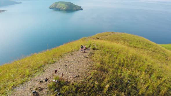 Aerial View Slow Motion: Couple Tourists Hiking on Mountain Top, Viewpoint on Lake Toba Indonesia