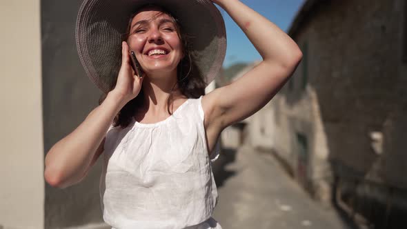Medium Shot of Happy Joyful Young Female Tourist Talking on Phone Standing on Sunny Summer Day on