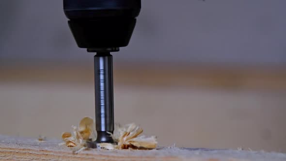 Drilling holes in wooden floor logs of the house with a puncher drill for the installation floor bra