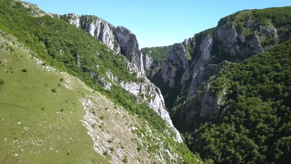 Drone flying toward the entrance to Turda Gorge near Transylvania, Romania. Steep hills leading towa