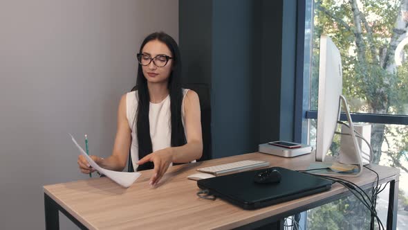 Serious Young Woman in Glasses Working in the Office