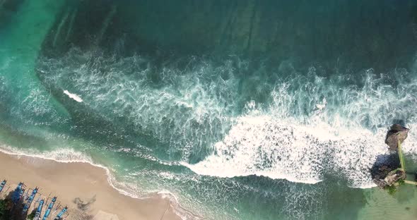 Aerial top down shot of white sandy SIUNG BEACH with crashing waves ending at shore in sunlight - YO