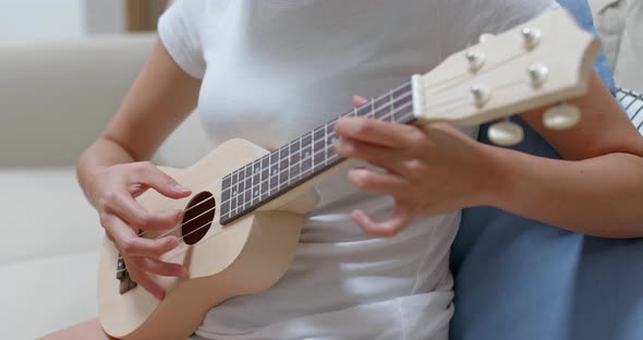 Woman play ukulele at home