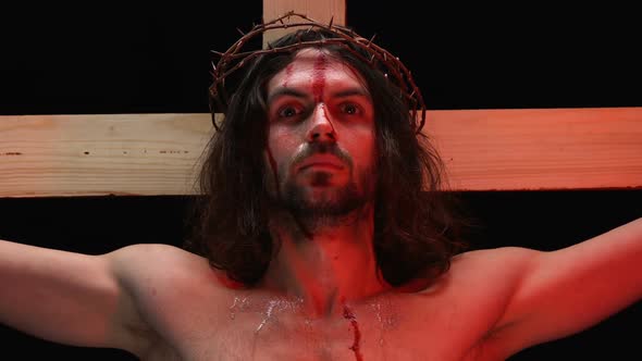 Jesus Christ Suffering Agony in Red Lights, Blood and Tears on Body, Crucifixion