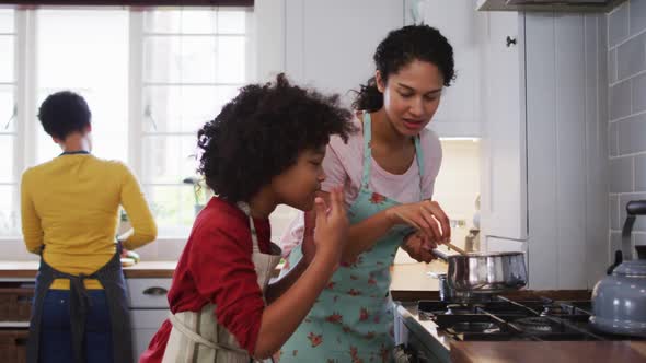 Mixed race lesbian couple and daughter preparing food in kitchen