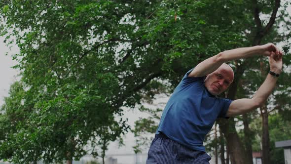 Old Man Warm Up His Back and Muscles Outdoor