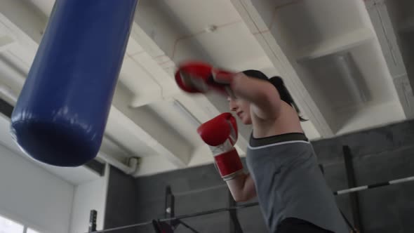 Female Boxer Punching Heavy Bag during Workout in Gym