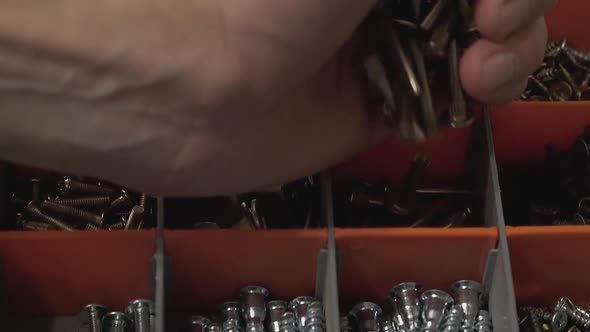 Master Who Produces and Installs Furniture Pours Many Bolts Into the Cell in the Suitcase. Close-up