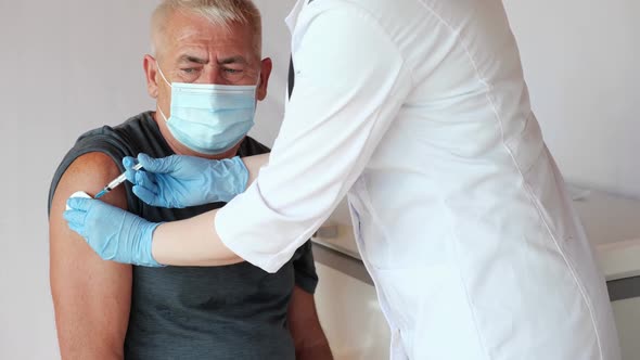 Doctor Vaccinating Senior Man In Clinic