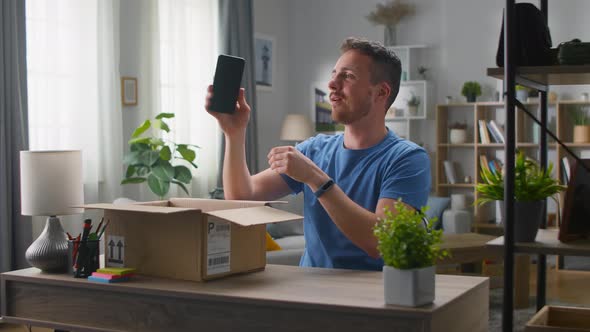 Handsome Young Man Takes a Smartphone Out of a Cardboard Box