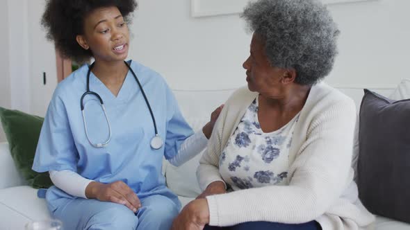 Caring african american female doctor and sad senior female talking