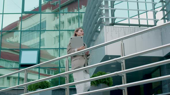 Business Woman with Computer in Hand Walks on Heels to a Business Meeting