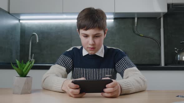 Portrait of Handsome Boy Playing Video Game with Smart Phone Indoors at Living Room