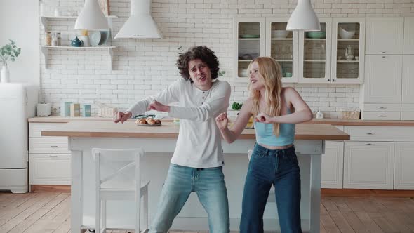 Happy Funky Young Romantic Couple Dancing Jumping in Kitchen