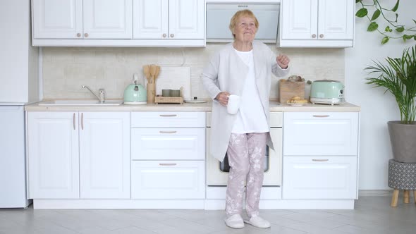 Happy Elderly Woman Dancing In Kitchen. Funny Grandmother.