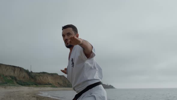Sportsman Practicing Hands Punches on Gloomy Beach