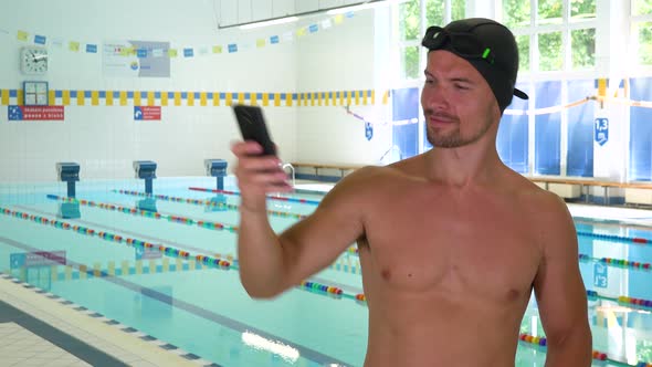 A Professional Swimmer Takes Selfies with a Smartphone at an Indoor Pool