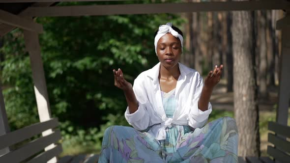 Front View Relaxed African American Confident Woman in Lotus Pose Meditating in Sunny Forest