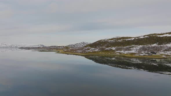 Calm aerial flight over fiord in arctic circle, snowy landscape; Norway