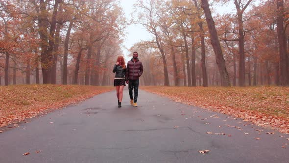 Interracial Love Concept. Beautiful Young Interracial Couple Walking on Road in the Foggy Autumn