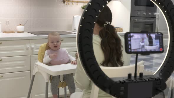 Recording Video with Mobile Phone and Ring Light of Mother Feeding Her Oneyearold Baby Boy with